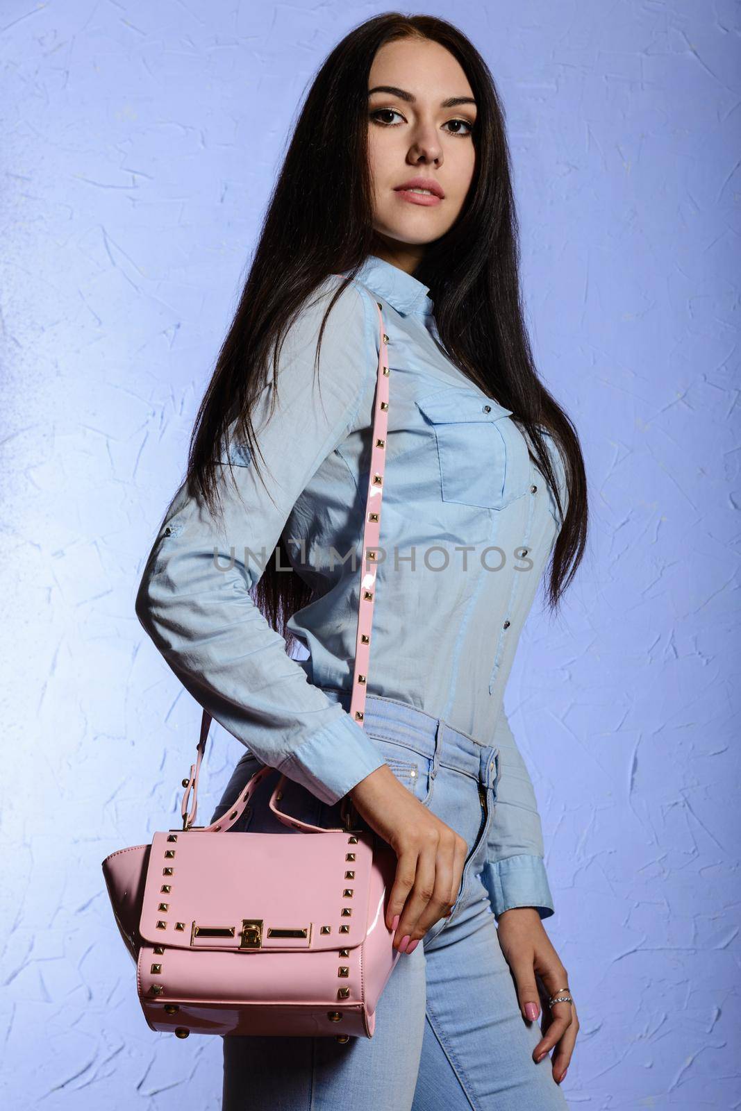 Attractive woman in jeans standing with a pink bag.