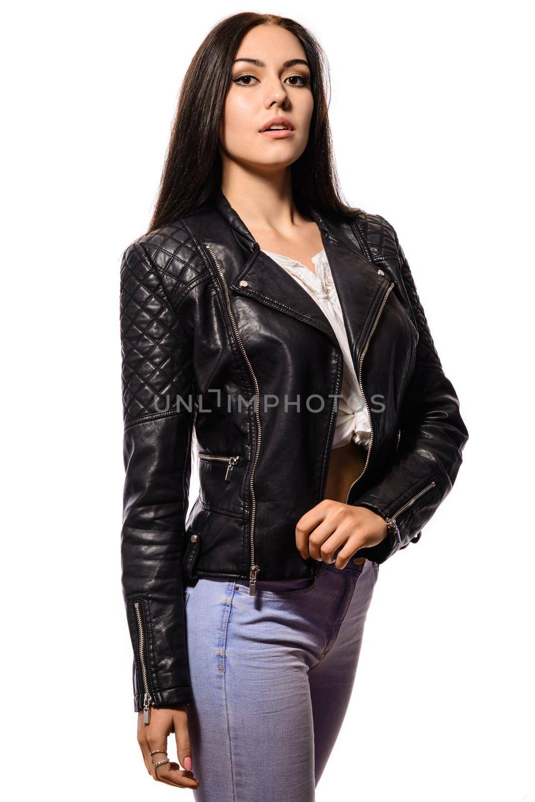 Beautiful slim young woman with long black hair standing in a black leather black leather jackets and jeans isolated on white