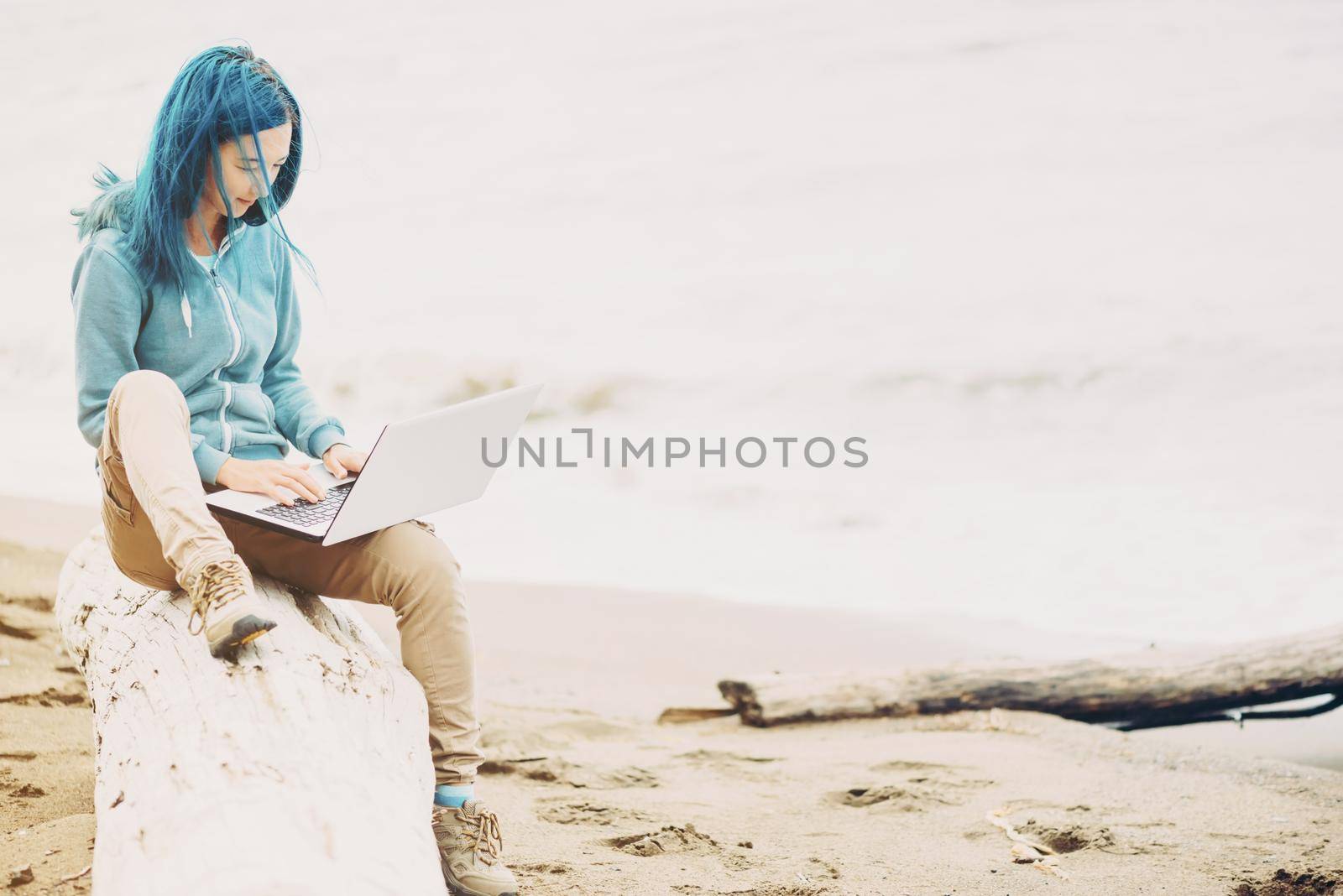 Freelancer girl sitting on beach and working on laptop near the sea. Freelance concept.