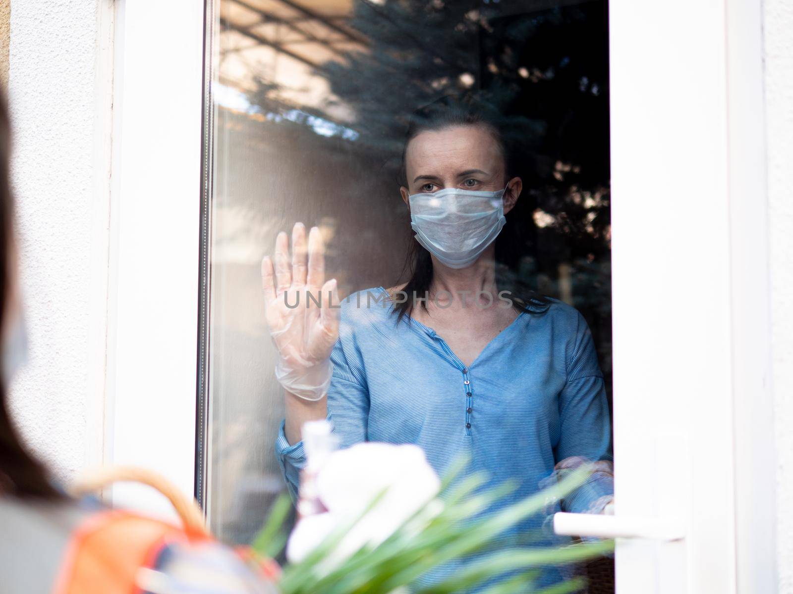 Food delivery during a pandemic and strict quarantine. A teenage volunteer girl delivered a basket of food to a woman in strict isolation. by Utlanov