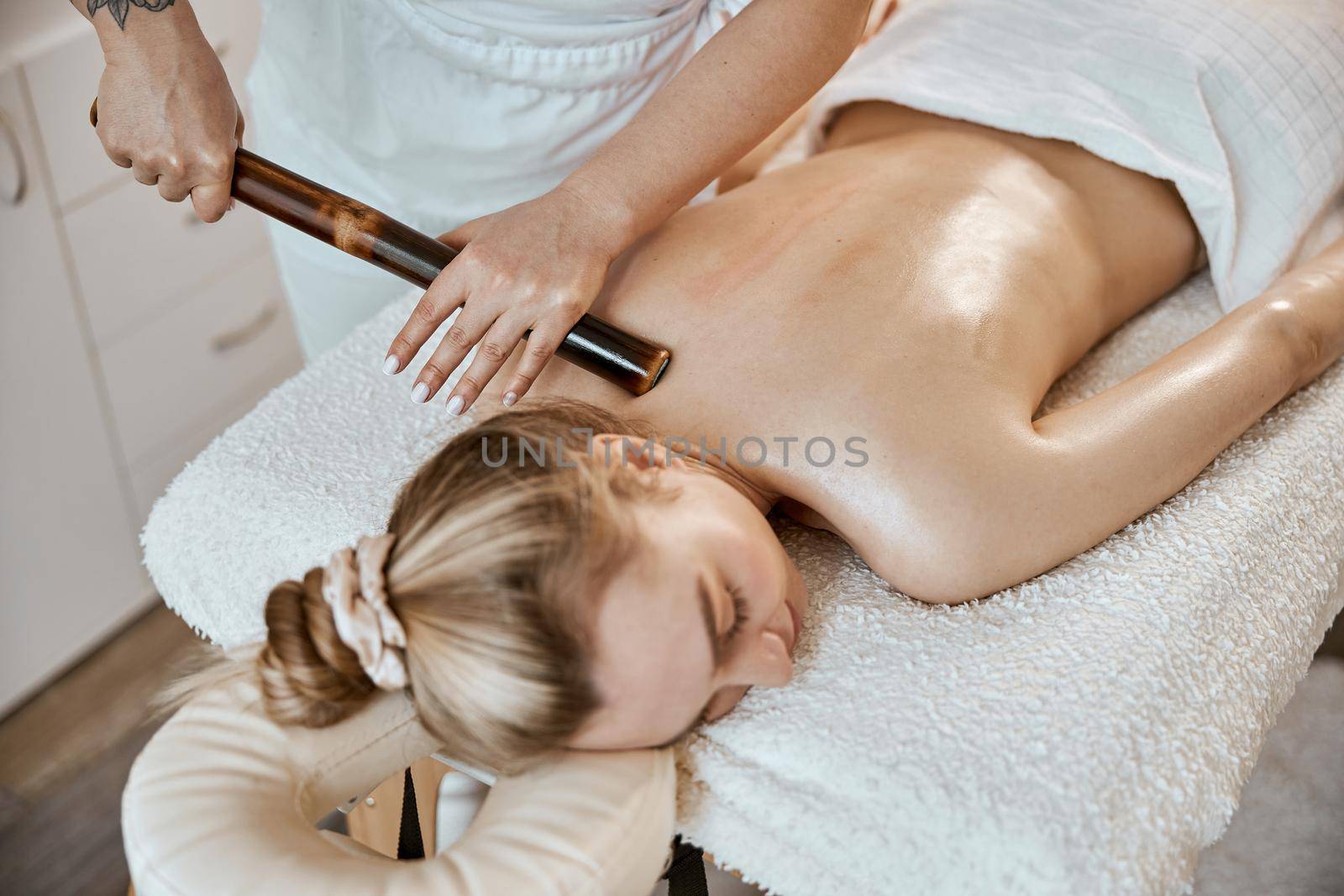 Professional confident massage master is doing procedures to caucasian woman in minimalistic modern cabinet