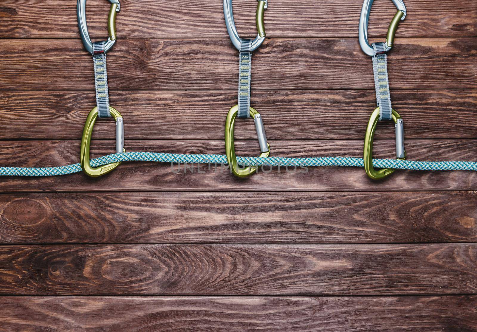 Rope with quickdraws on a wooden background, top view. Copy-space in lower part of the image.