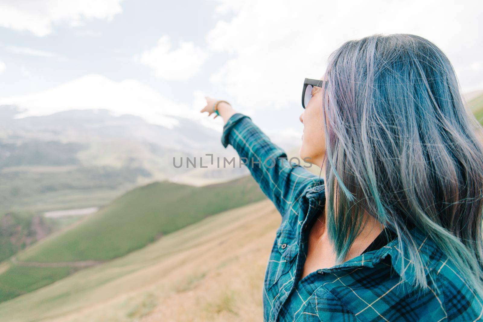 Explorer young woman pointing at snowy high mountain outdoor.