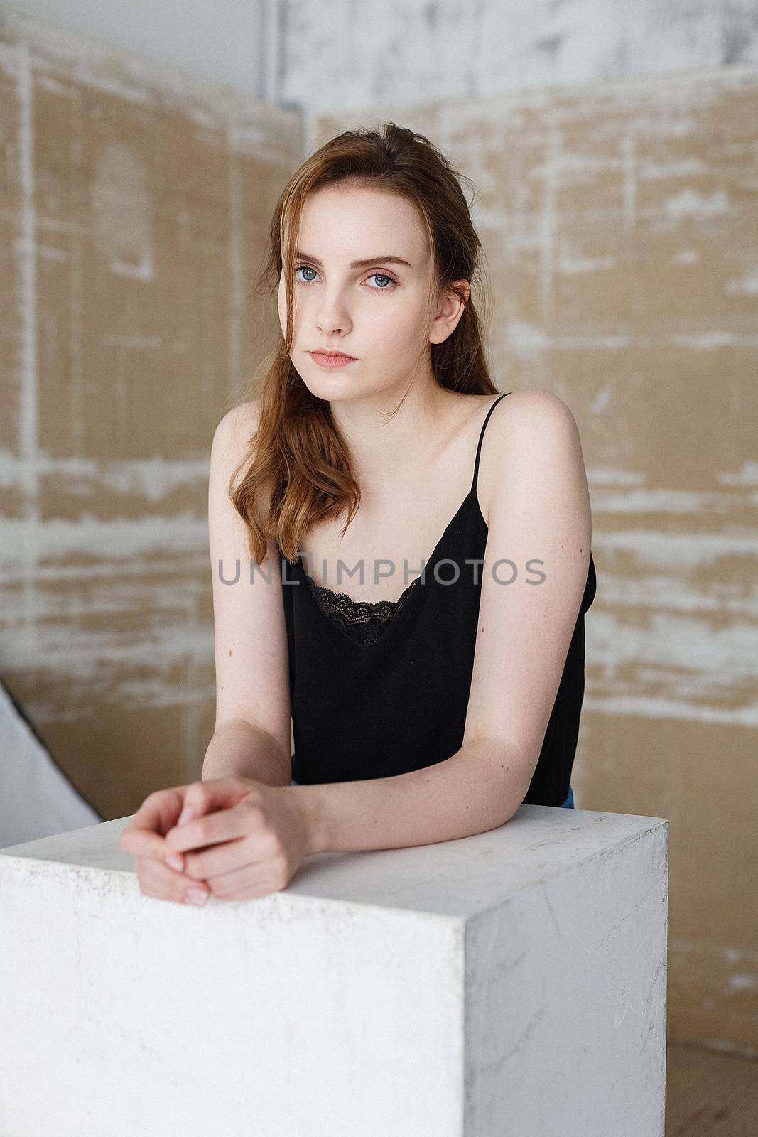 Beautiful young woman in black top with blue eyes, indoors portrait of cute thoughtful model. caucasian skinny female with long brown hair on abstract background. natural pretty lady posing at studio