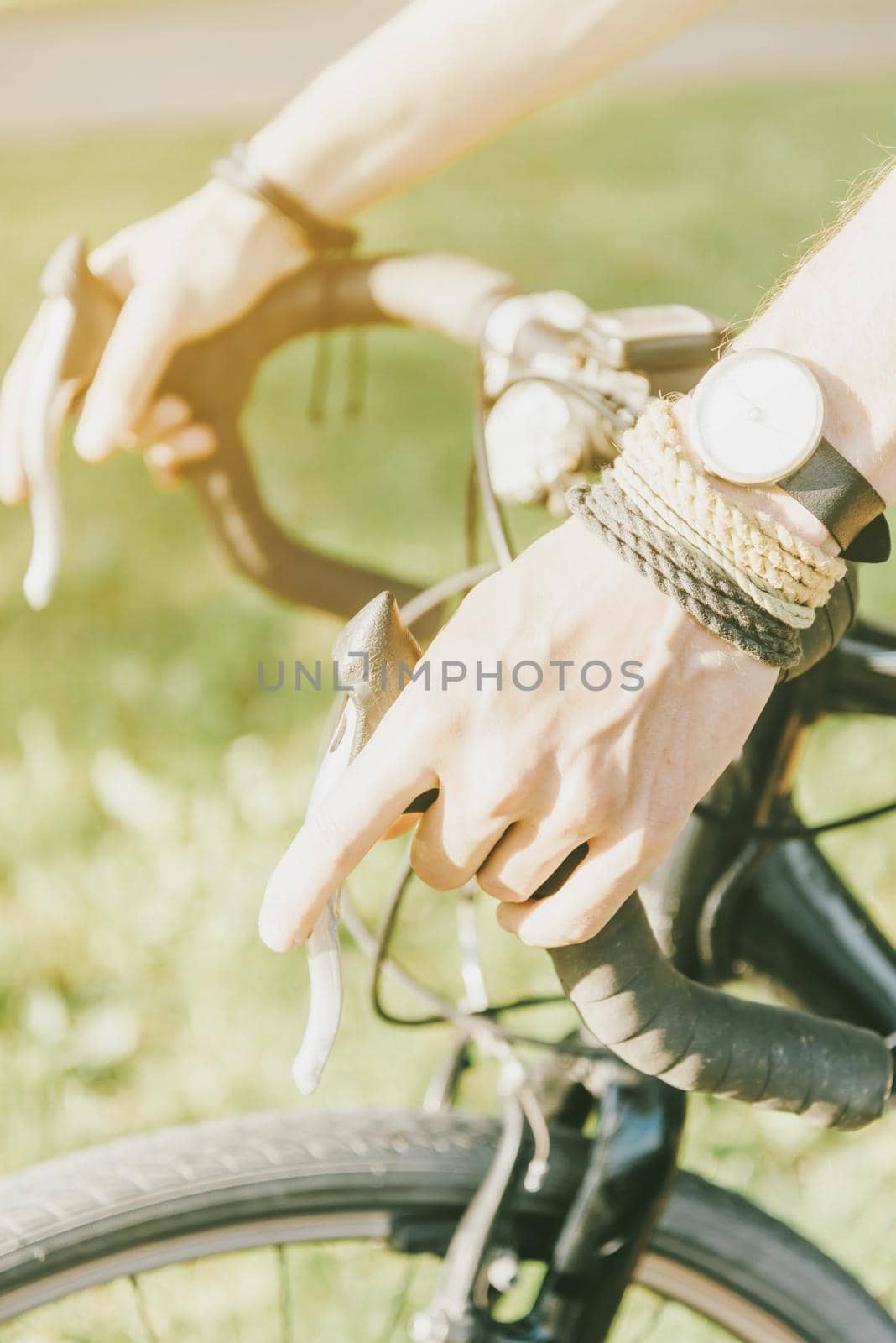Male hands holding handlebar of bicycle in summer outdoor, close-up.