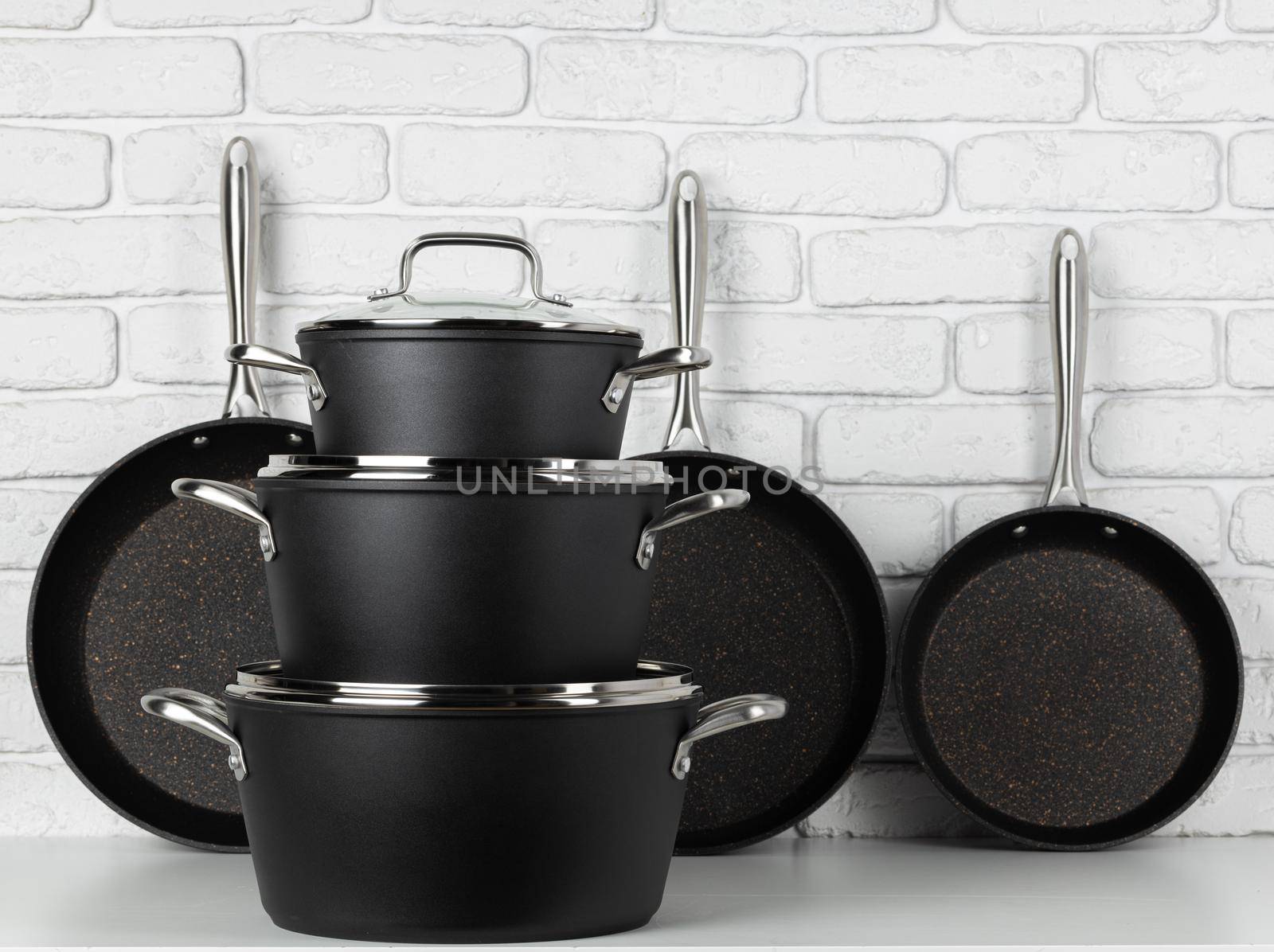 Set of cookware on table against white brick wall front view