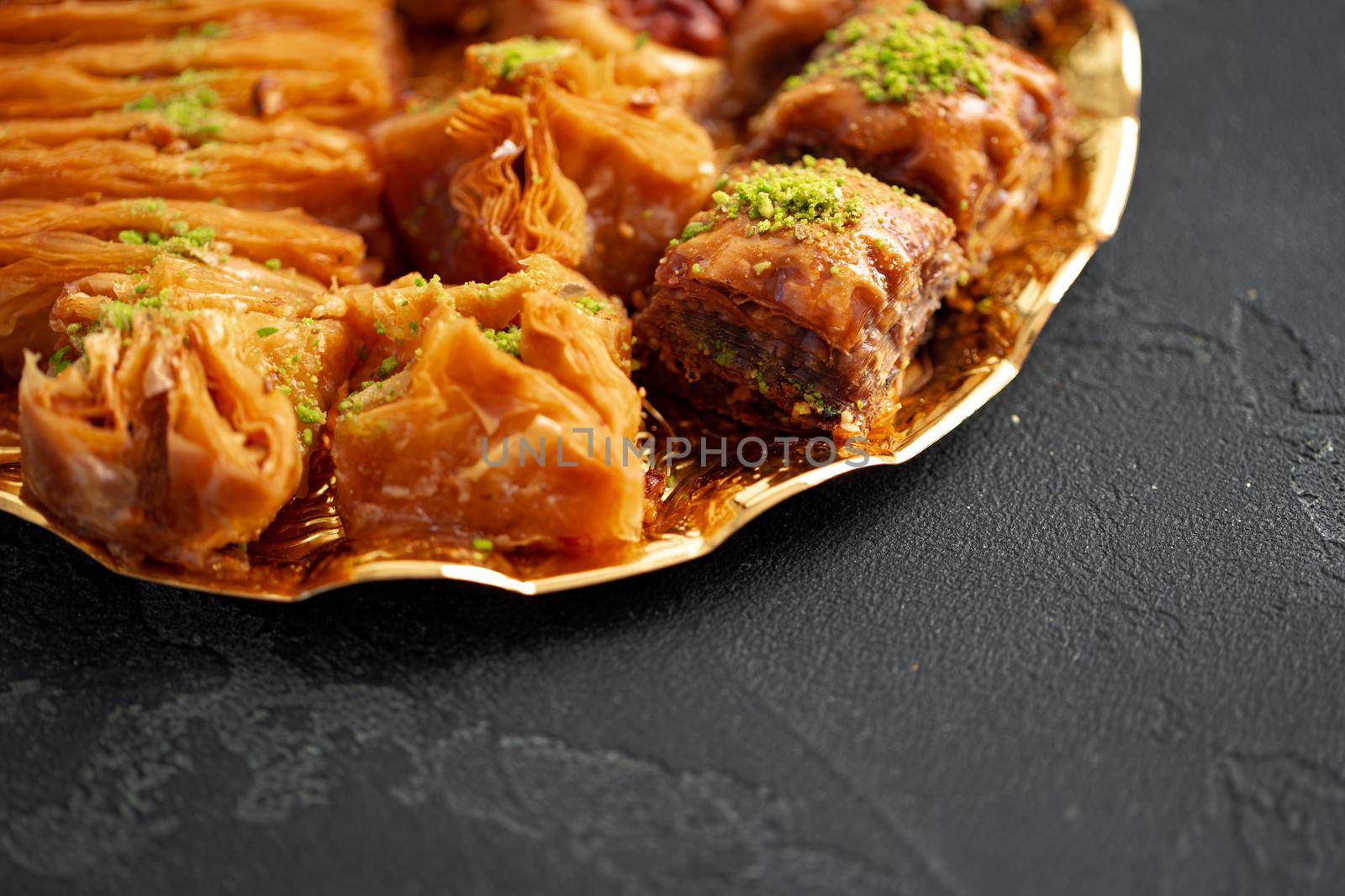 Delicious baklava dessert in oriental setting on black background, close up