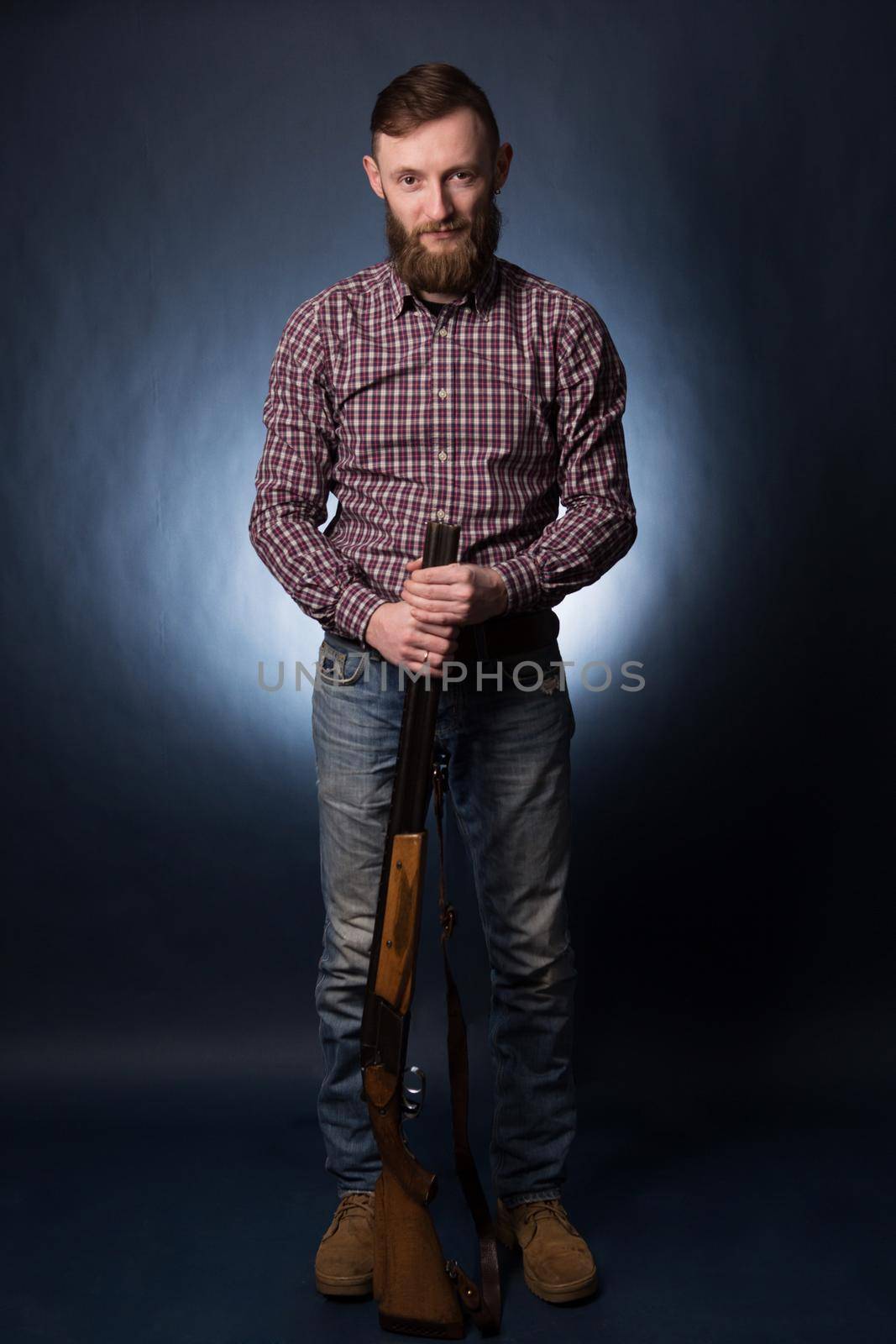 Man in a plaid shirt with shotgun on a dark background