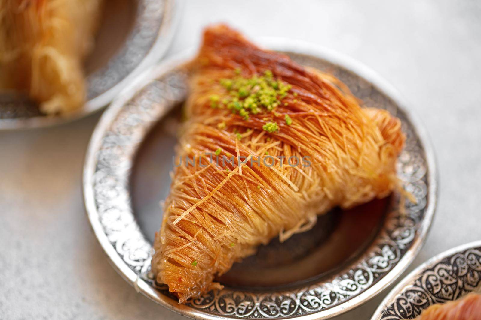 Turkish baklava on oriental metal plate on white table, close up