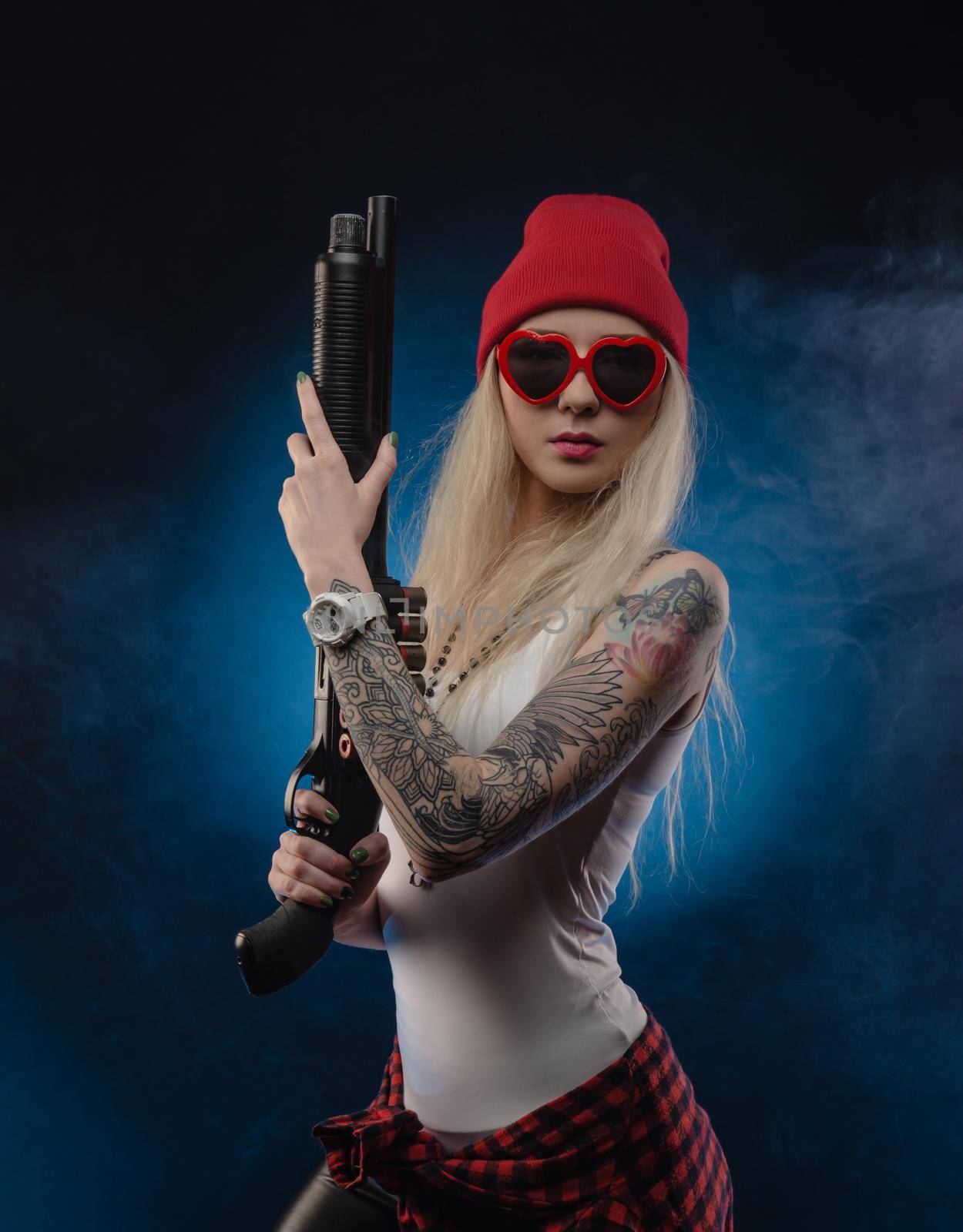 bright blonde in a red hat with a shotgun on a dark background