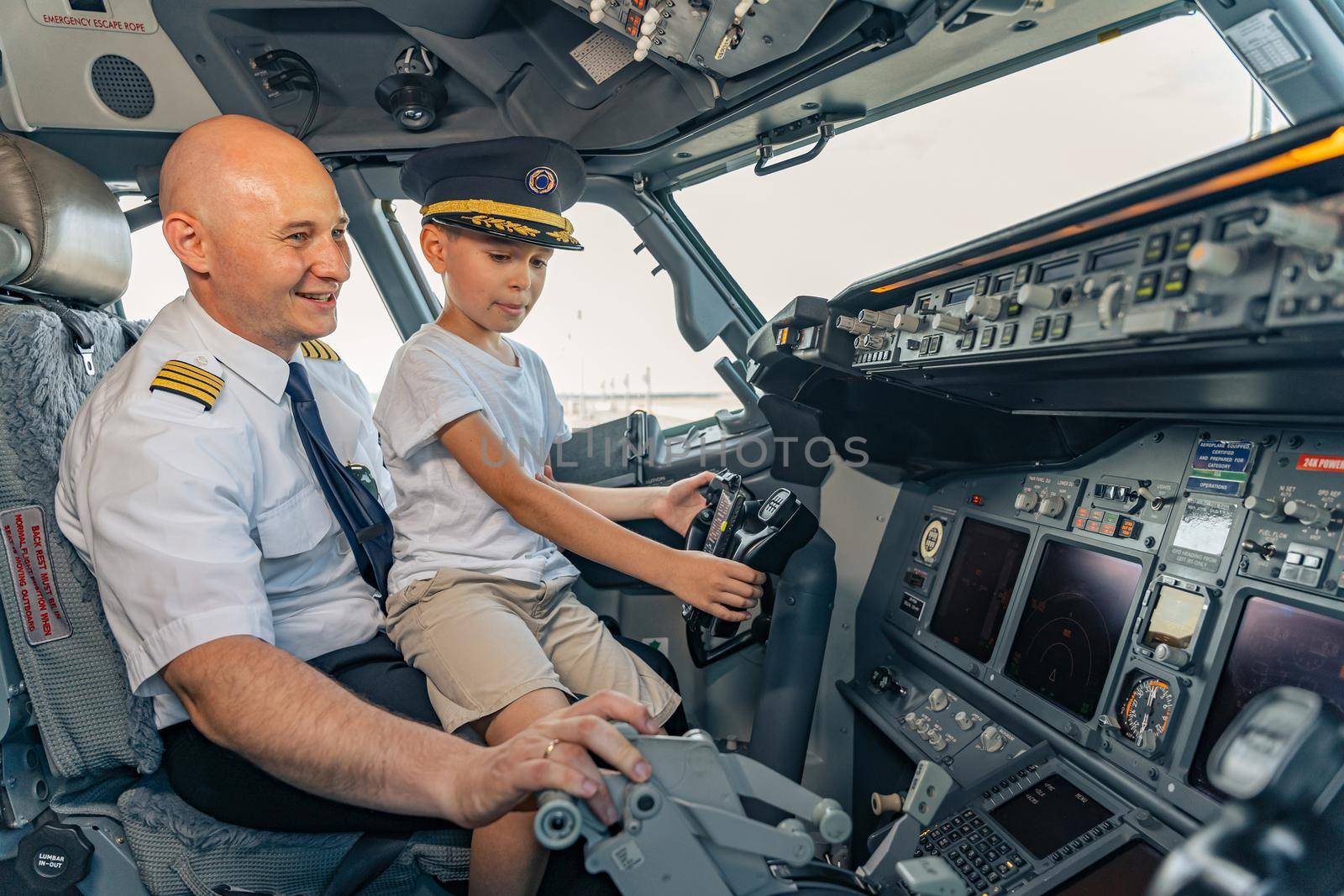 Smiling mature pilot and kid sitting in cabin by Yaroslav_astakhov
