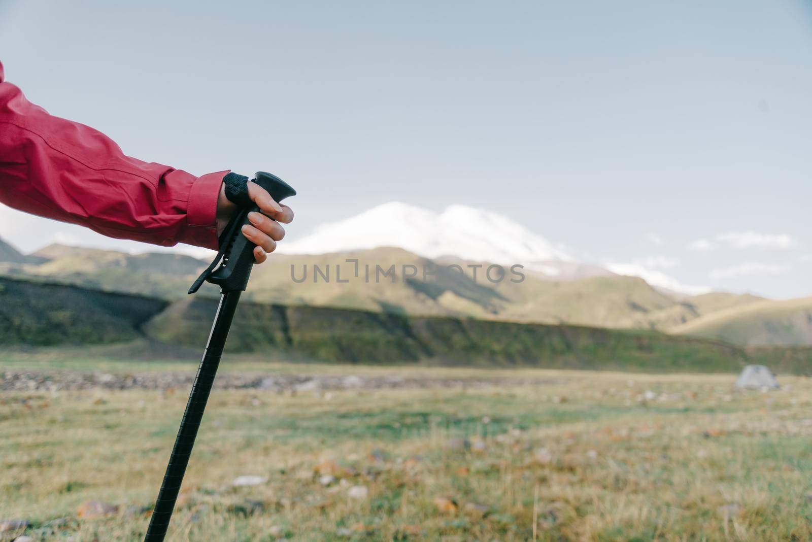 Female hand with trekking pole on background of mountain Elbrus.