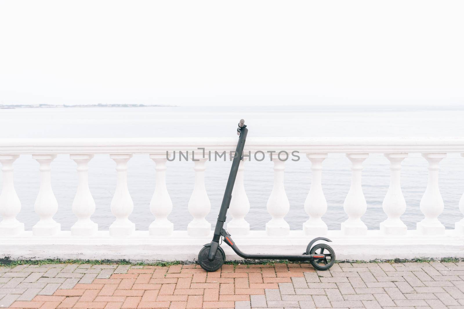 Ecological transport electric scooter on embankment in front of sea. No people.