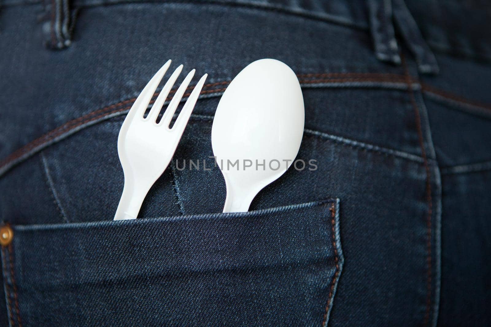 reusable plastic spoon and fork at the pocket. safe environment. Take Out Food Concept with Denim Jeans with a white Fork and Spoon in the Pocket. fast food concept.