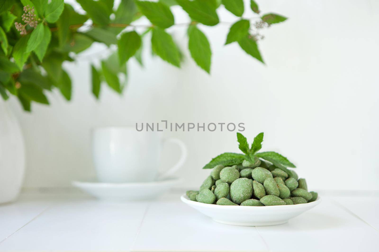 green nuts with wasaby or canabis coat on white plate on white background. Selection of healthy food for heart, life concept. eco nutrition.