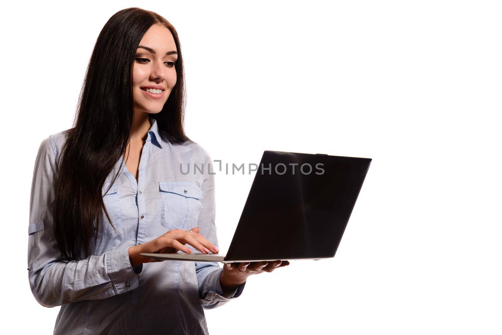 Portrait of charming smiling brunette in a denim shirt. He holds a laptop in the hands of