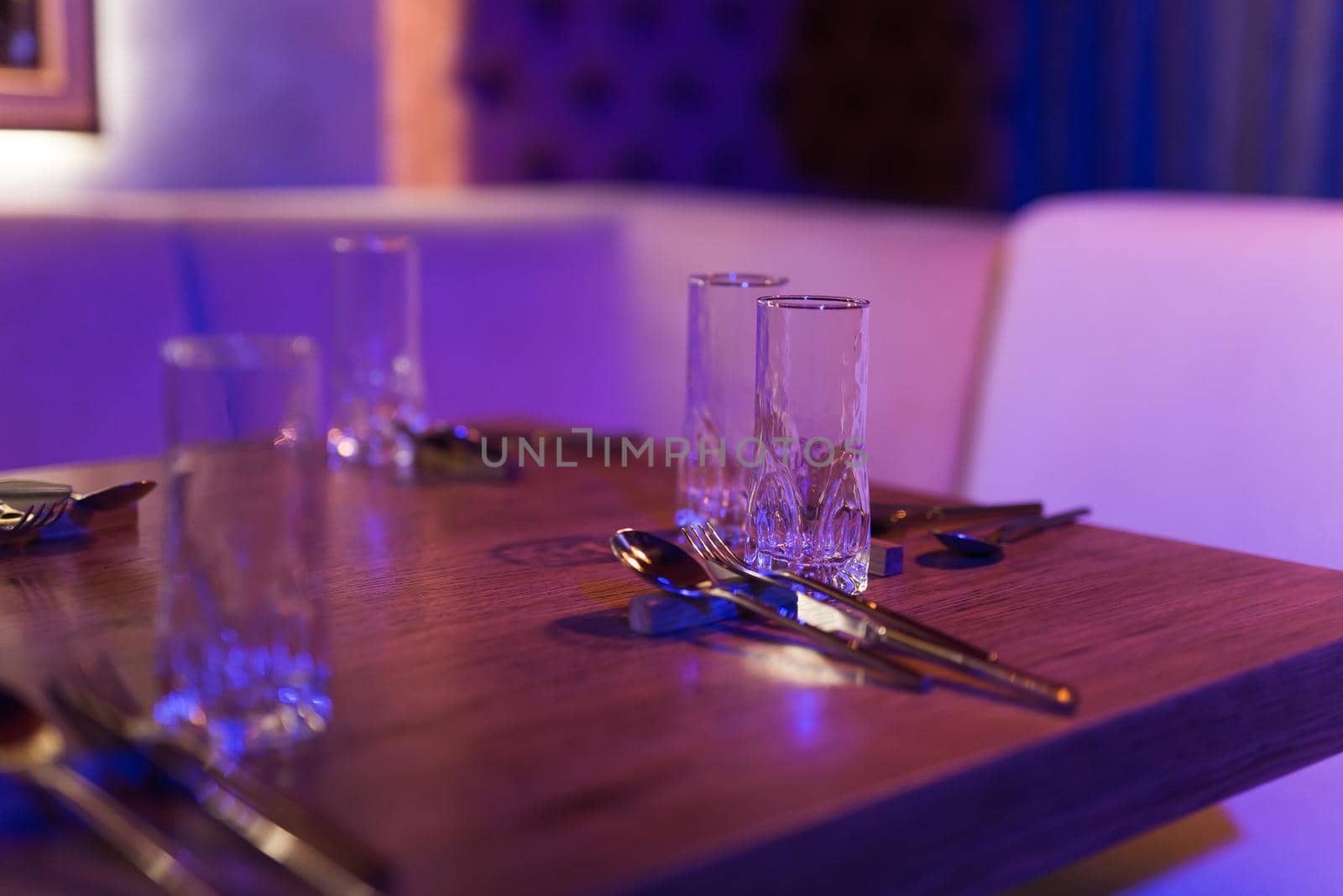 Served table with glasses and cutlery in a restaurant for dinner, closeup view by Satura86