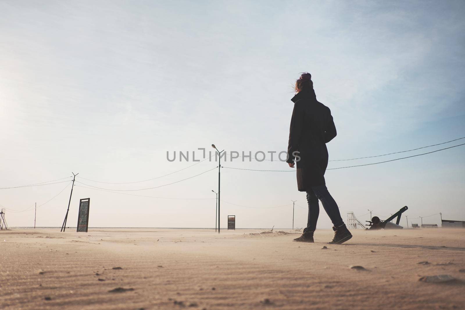 Young woman wearing in coat walking in the desert.