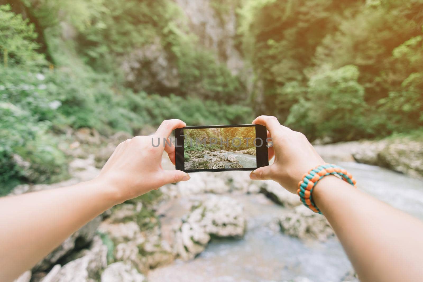 Traveler woman taking a photo with smartphone river in summer, point of view.