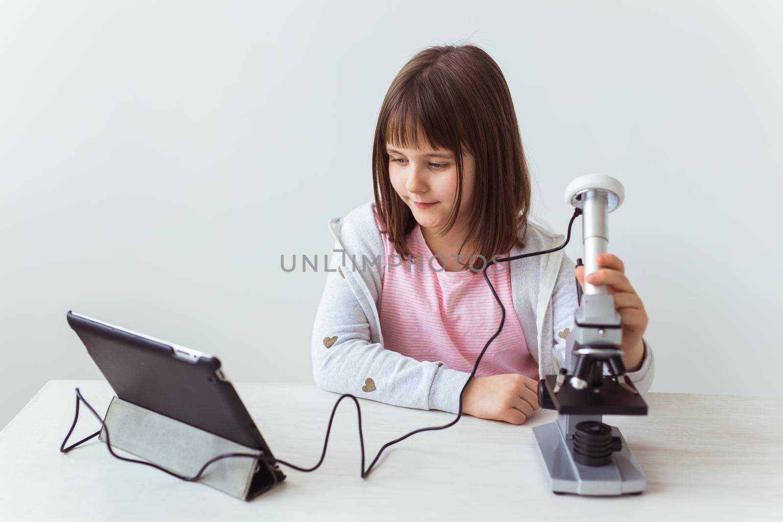 Portrait of cute little child doing homework with a digital microscope. Technologies, science and children concept. by Satura86
