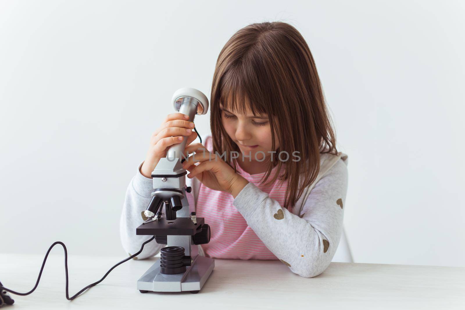 Portrait of cute little child doing homework with a digital microscope. Technologies, science and children concept. by Satura86