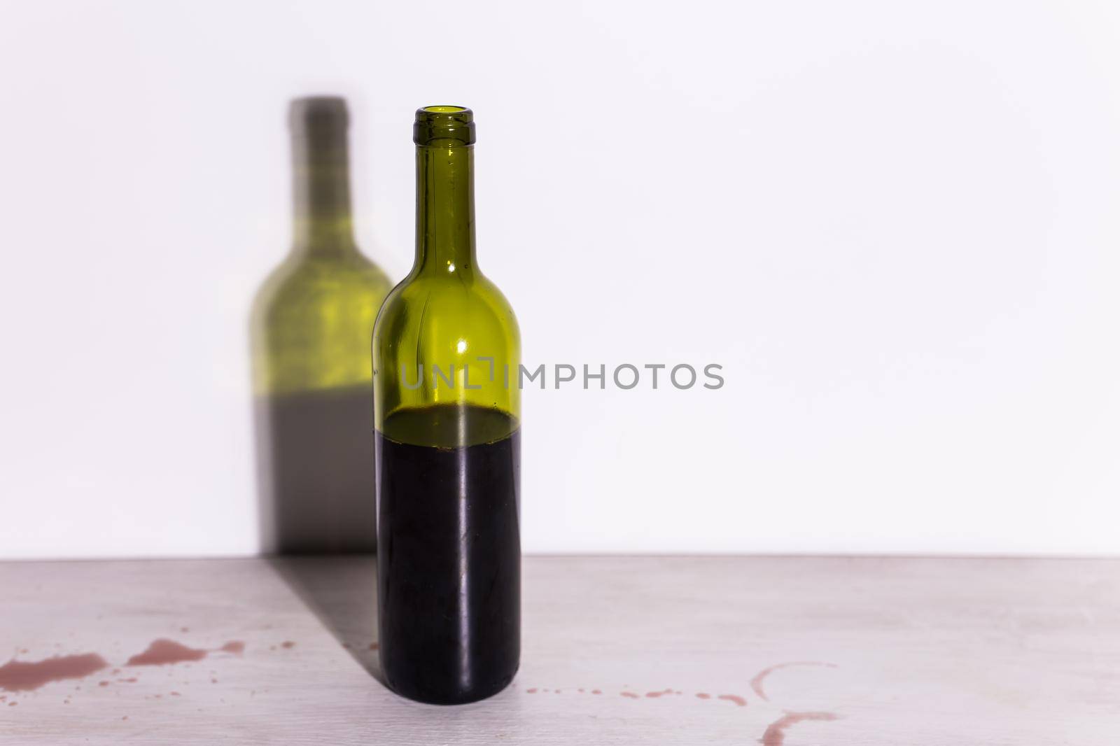 Bottle with wine, red puddle of wine on the table. Cleaning after party concept. by Satura86