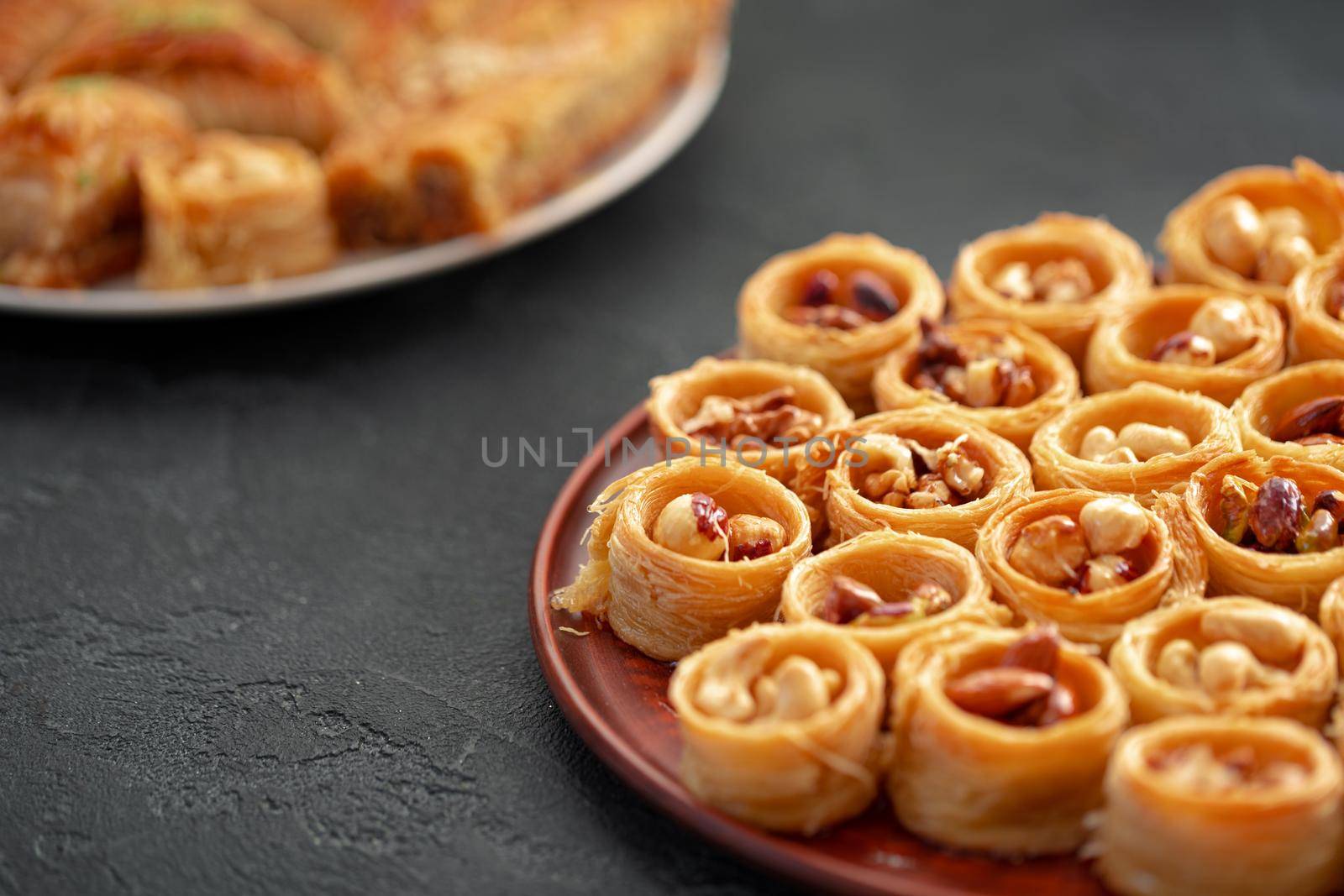 Delicious baklava dessert in oriental setting on black background, close up