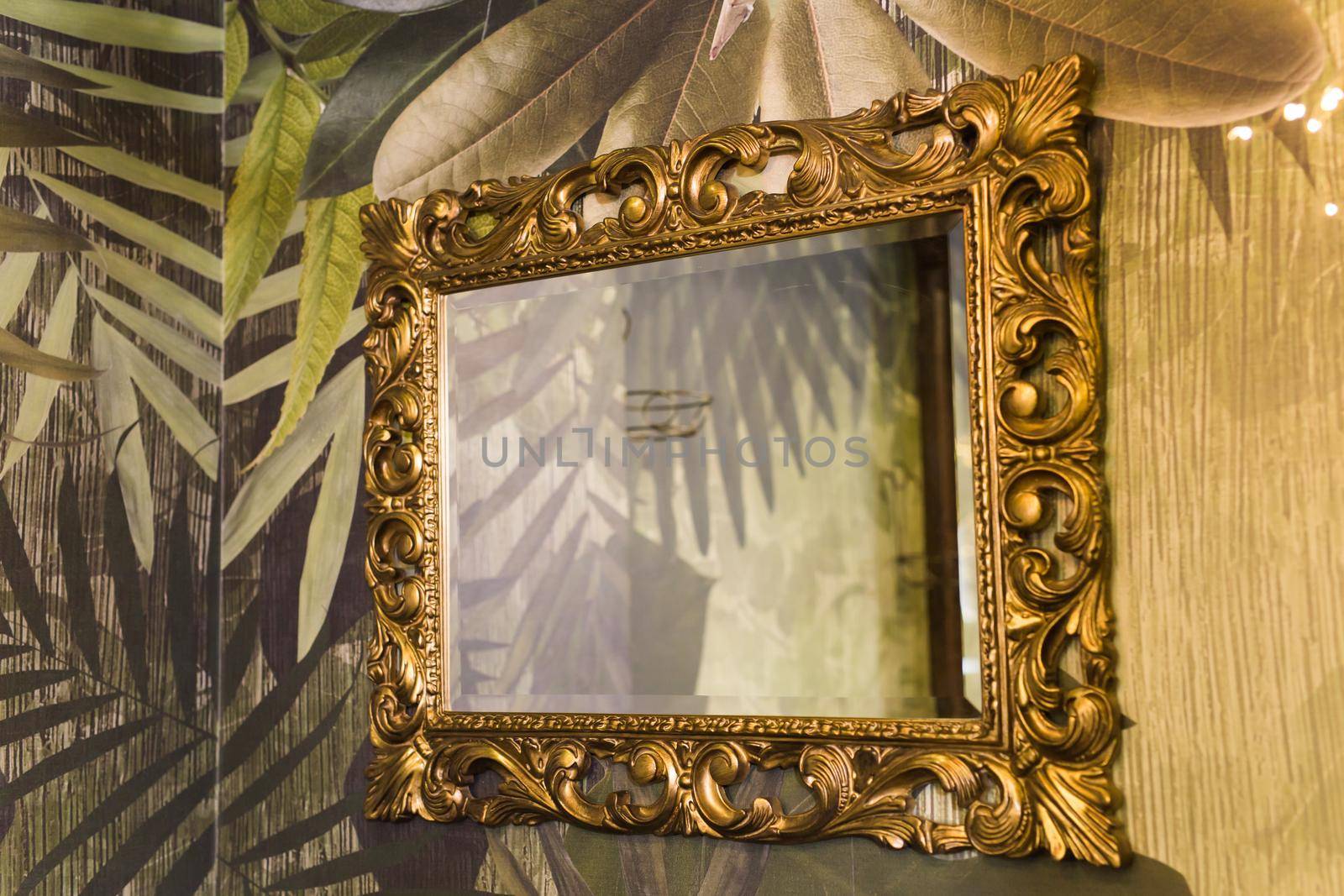 Luxury vintage mirror with gold frame on the wall. Isolated inside.