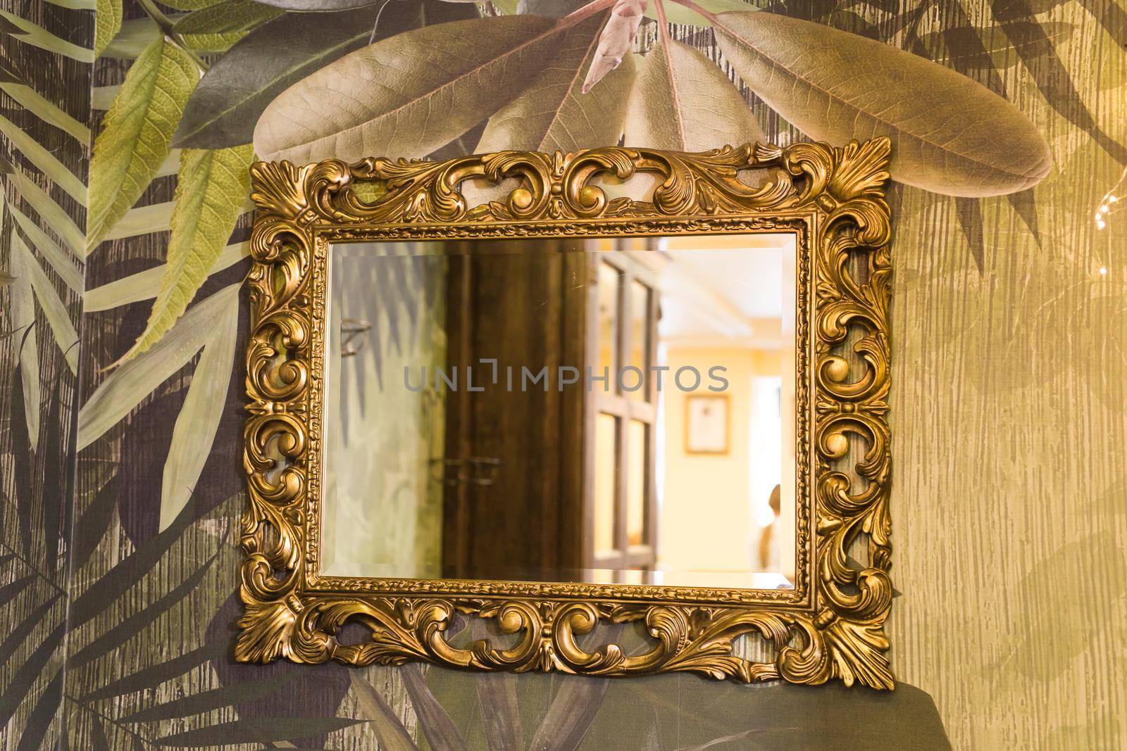 Luxury vintage mirror with gold frame on the wall. Isolated inside.