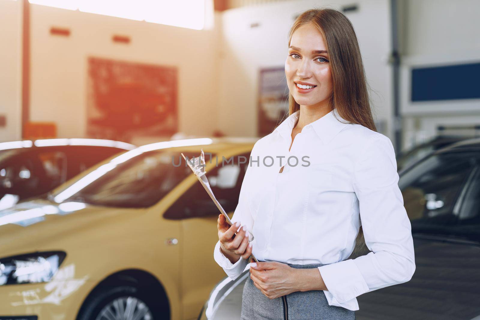 Happy beautiful young woman car dealer in showroom close up