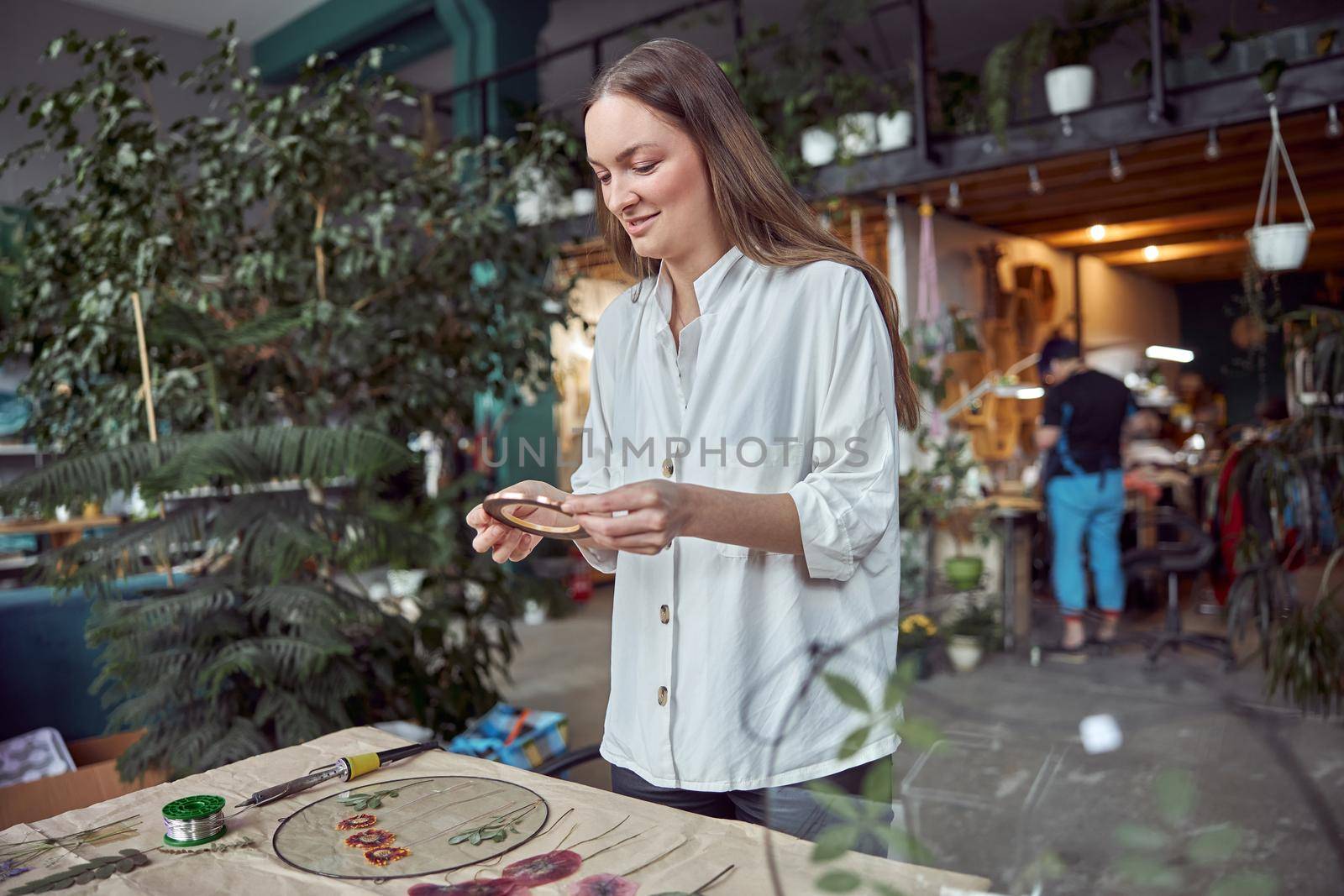 Confident female florist is working with dryed flowers in cozy flower shop