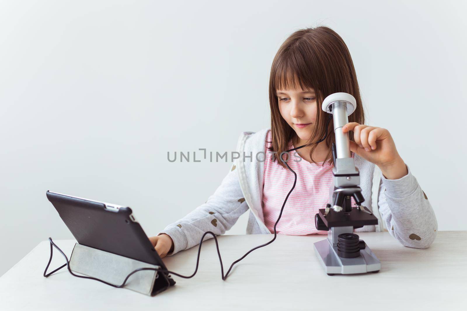 Portrait of cute little child doing homework with a digital microscope. Technologies, science and children concept. by Satura86