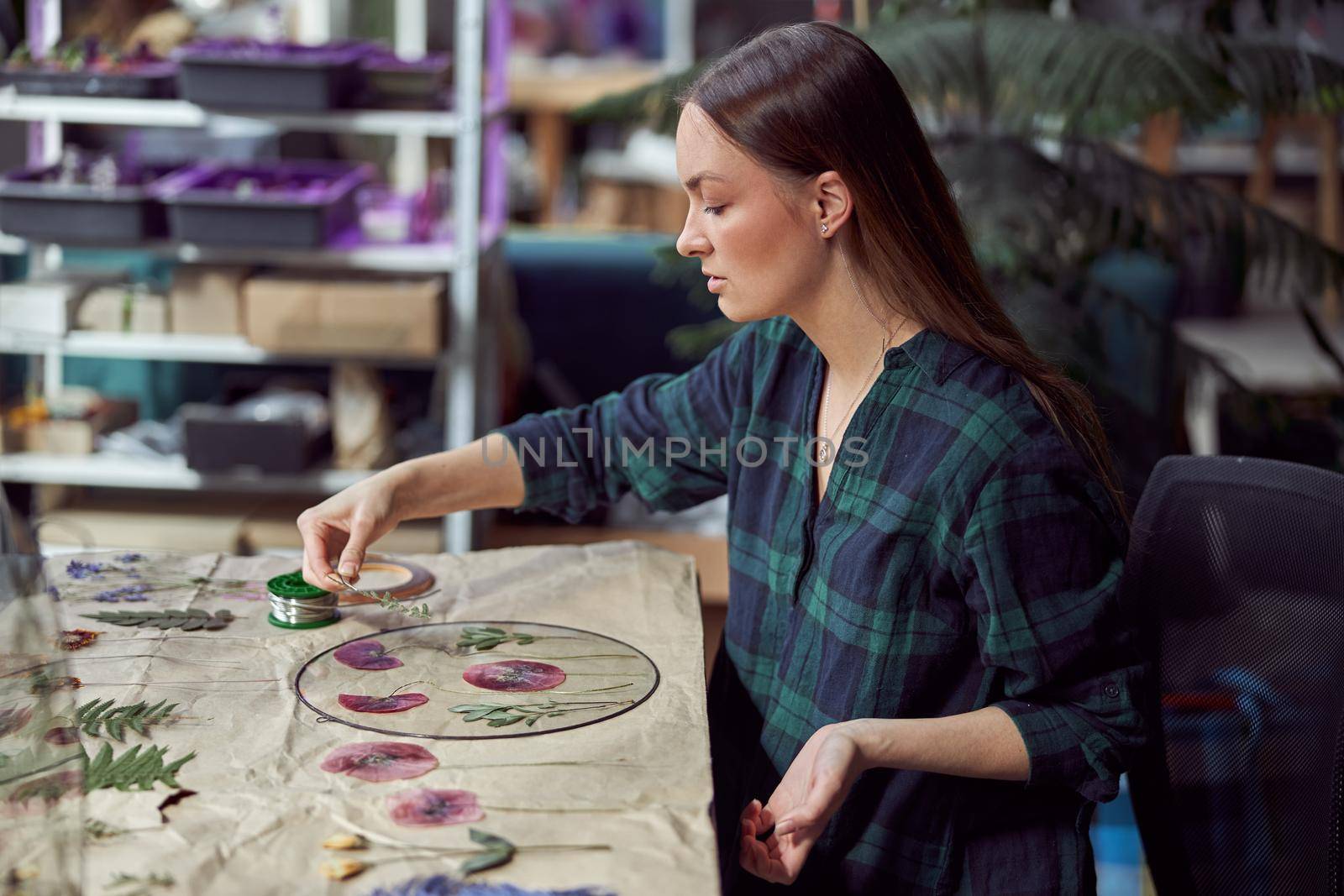 Confident female florist is working with dryed flowers in cozy flower shop