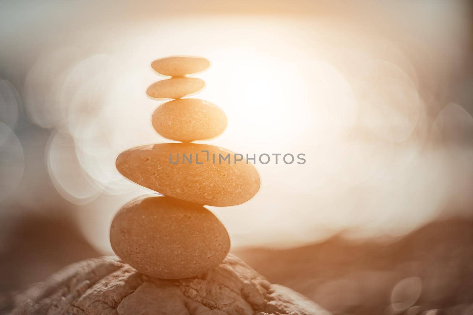 Balanced rock pyramid on the pebble beach on sunset. Selective focus Abstract bokeh from Sea foam on the background. Zen stones on the sea beach, meditation, spa, harmony, calmness, balance concept by panophotograph