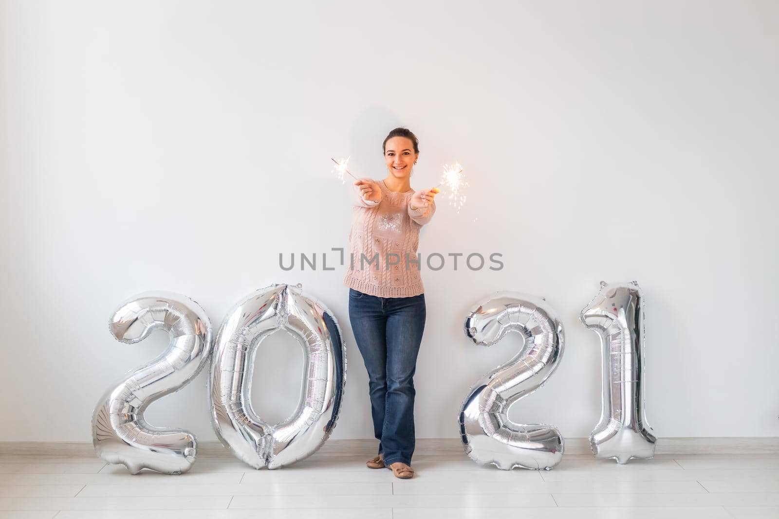 New Year celebration and party concept - Happy young woman with sparklers near silver 2021 balloons on white background. by Satura86