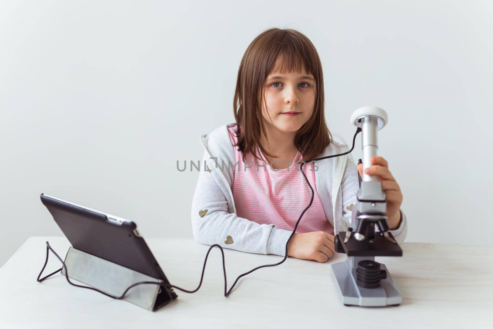 Schoolgirl using microscope in science class. Technologies, lessons and children concept. by Satura86