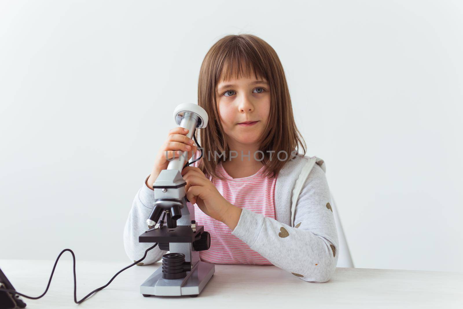 Portrait of cute little child doing homework with a digital microscope. Technologies, science and children concept. by Satura86