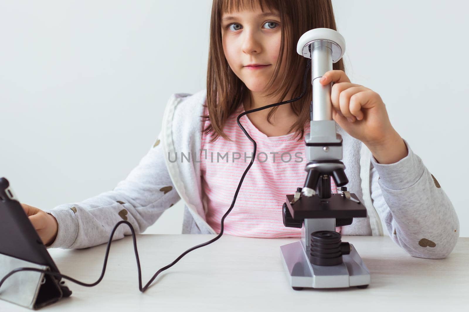 Child girl in science class using digital microscope. Technologies, children and learning.