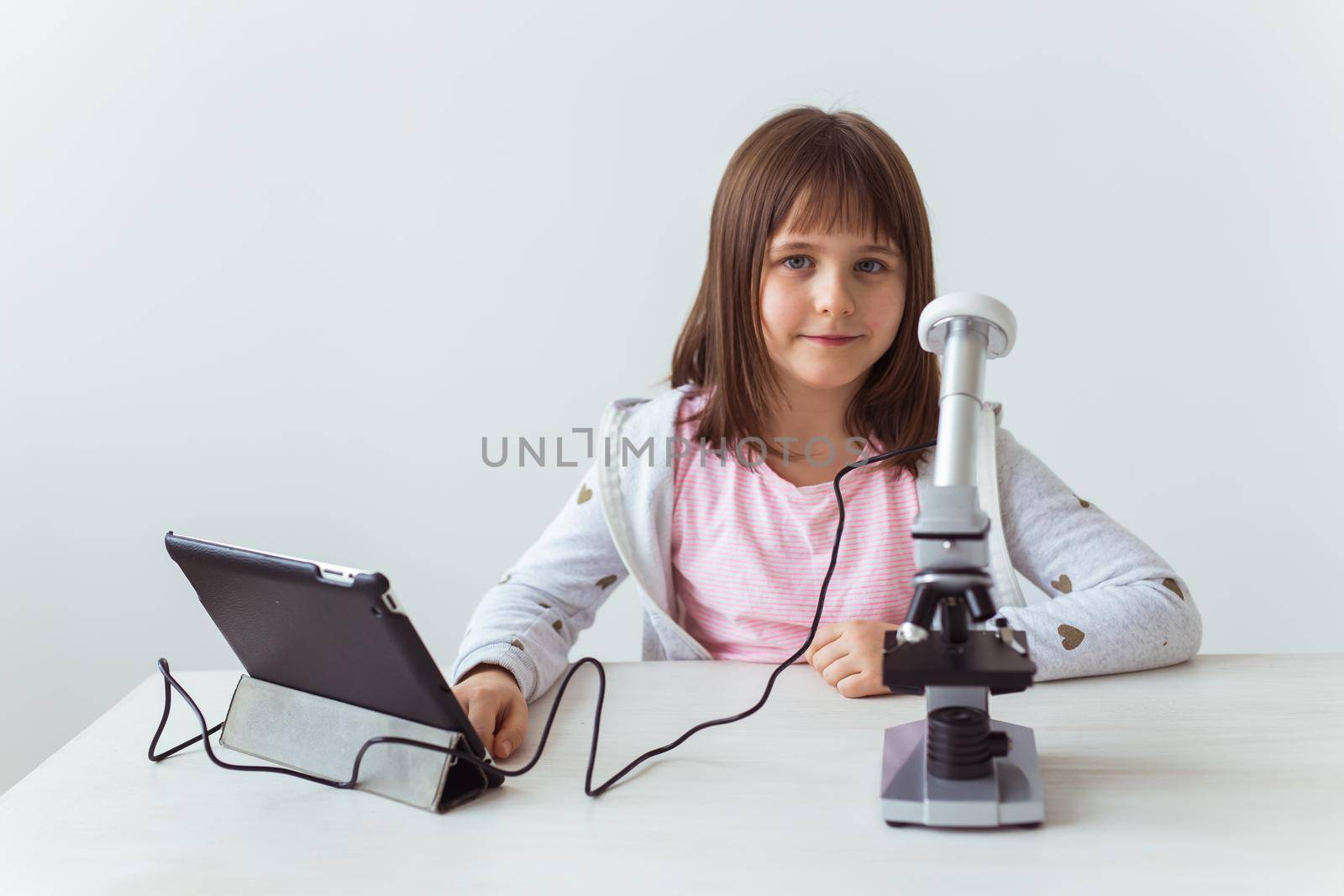 Schoolgirl using microscope in science class. Technologies, lessons and children.