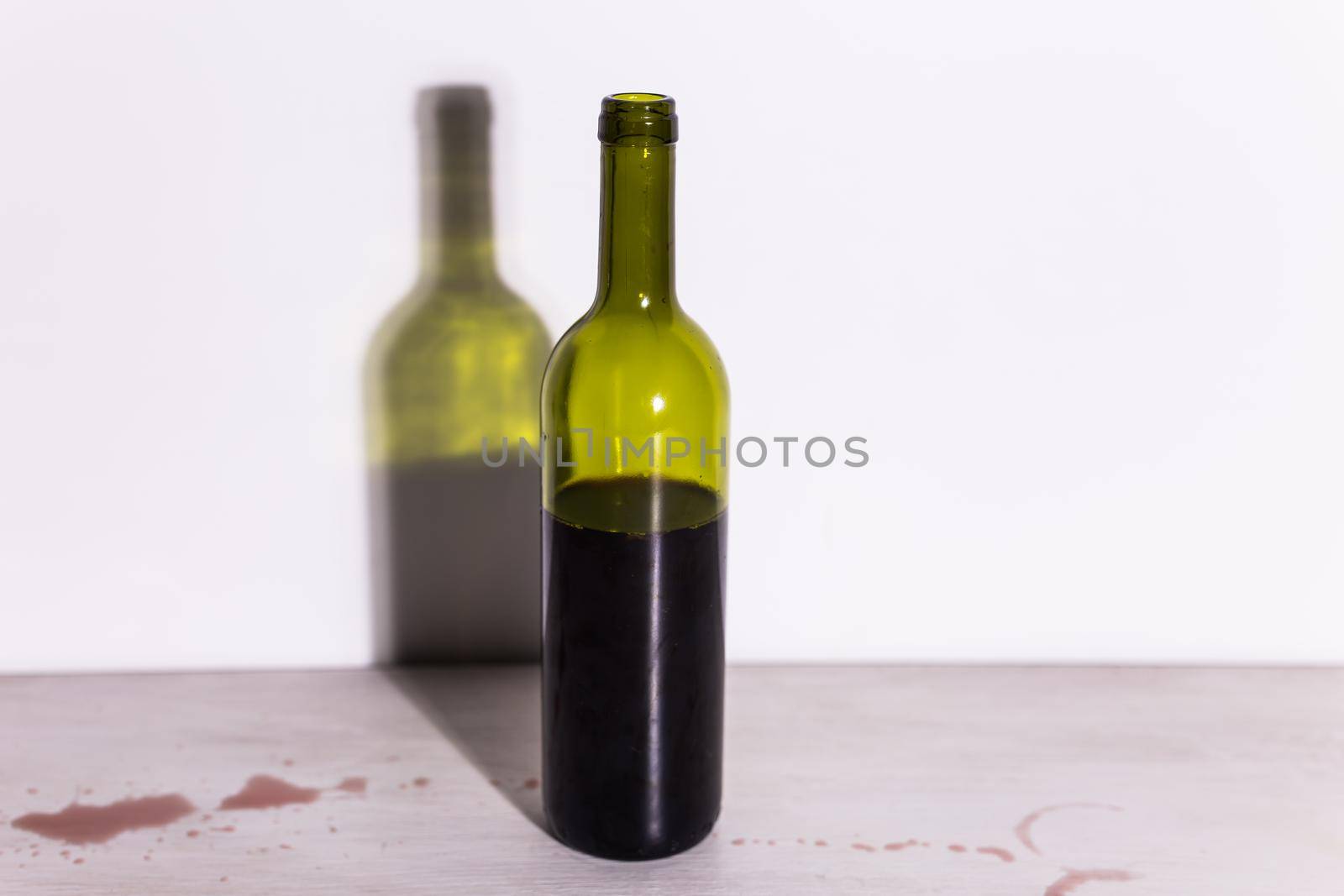 Bottle with wine and glass, red puddle of wine on the table. Cleaning after party concept