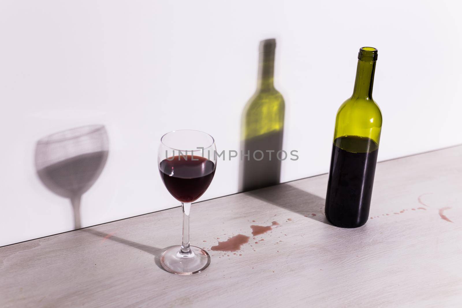 Bottle with wine and glass, red puddle of wine on the table. Cleaning after party concept. by Satura86