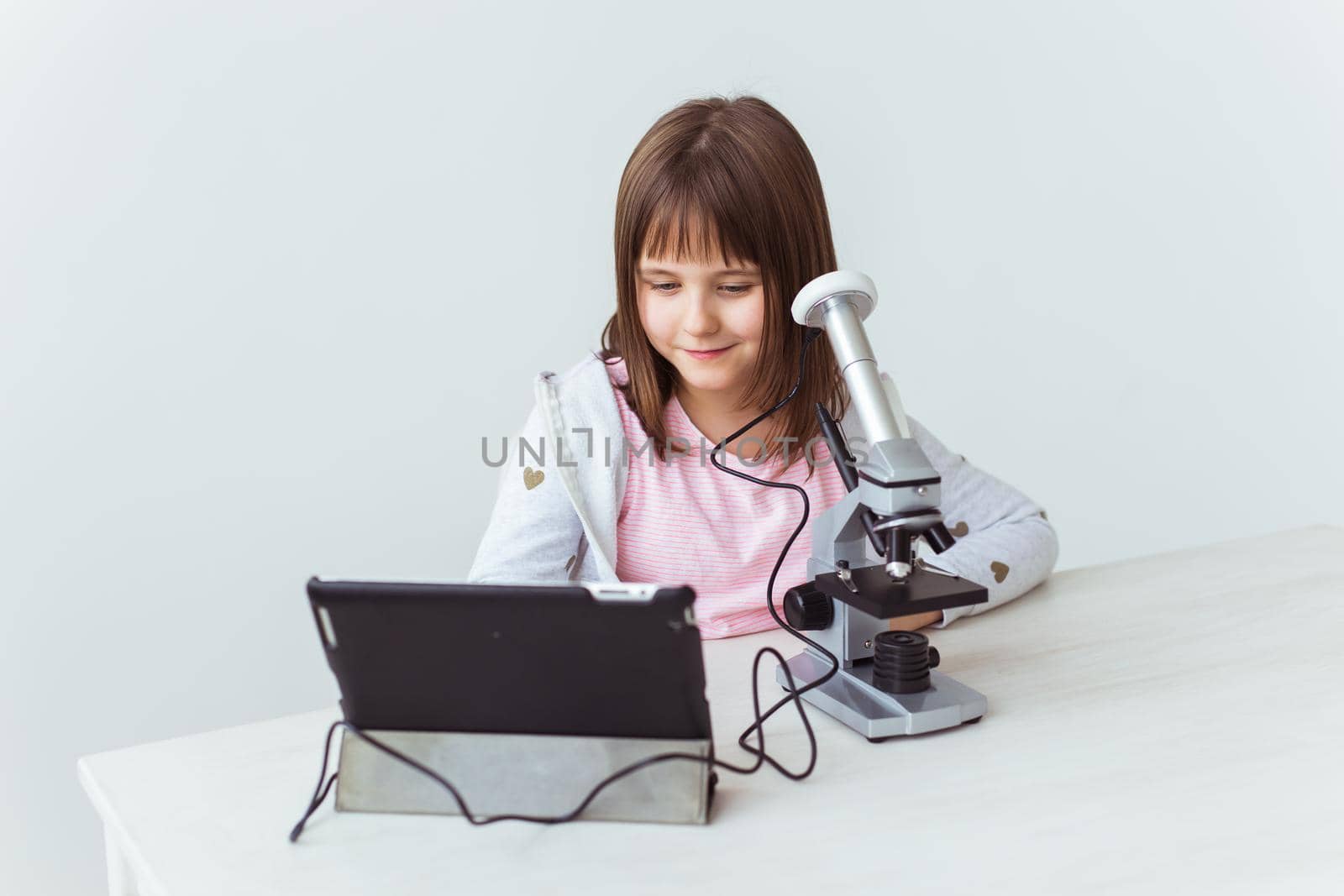 Child girl in science class using digital microscope. Technologies, children and learning.