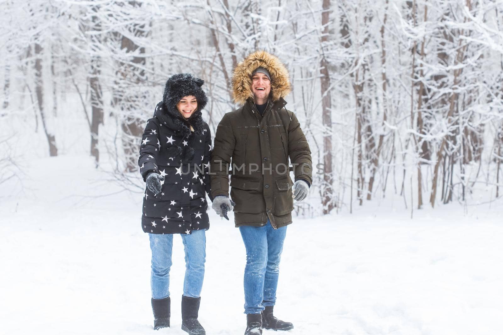 Young couple in love walks in the snowy forest. Active winter holidays