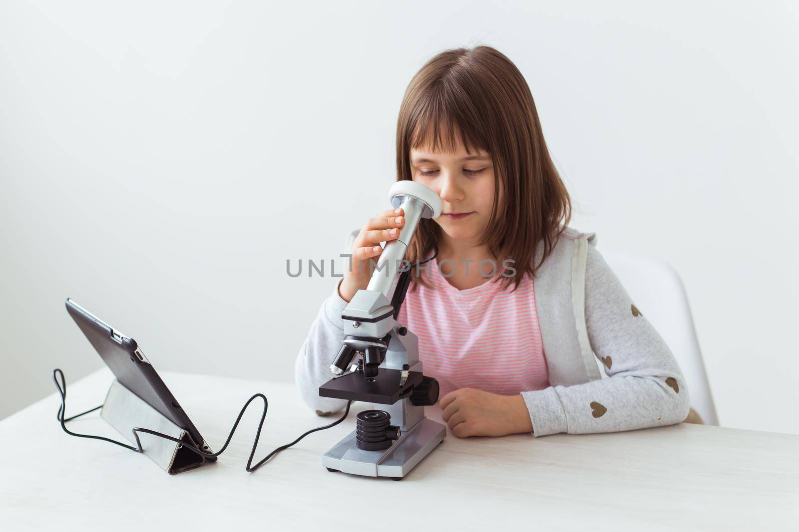 Portrait of cute little child doing homework with a digital microscope Technologies, science and children.