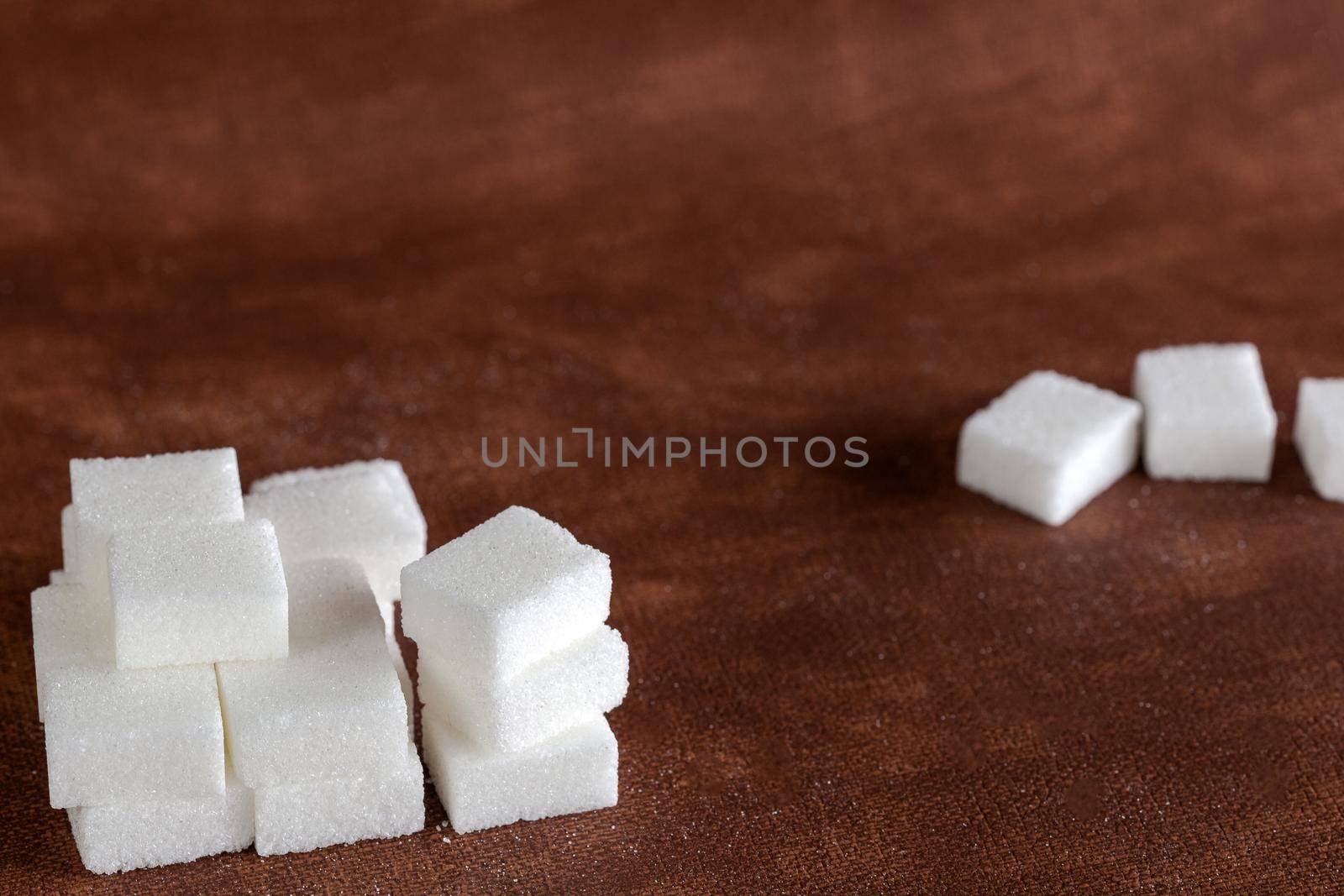 Sugar cubes with spoon top view on brown natural colored background texture with copy space, Sugar,sweet,health,food concept food