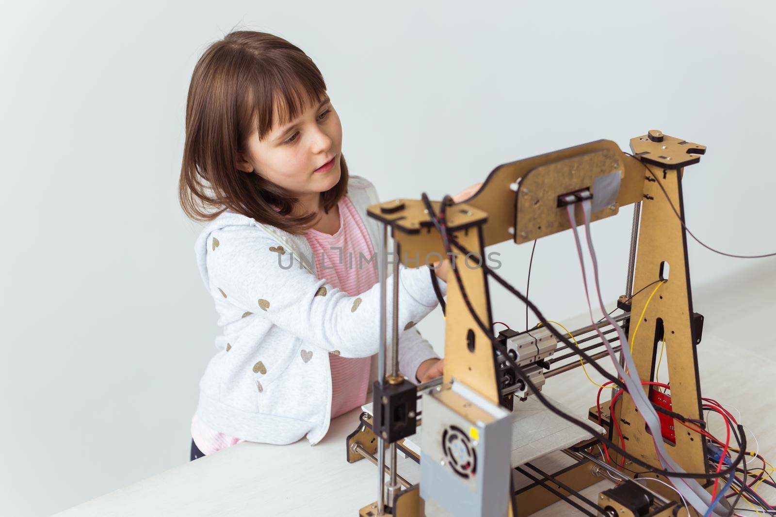 Cute girl with 3d printed shutter shades is watching her 3d printer as it prints her 3d model. by Satura86