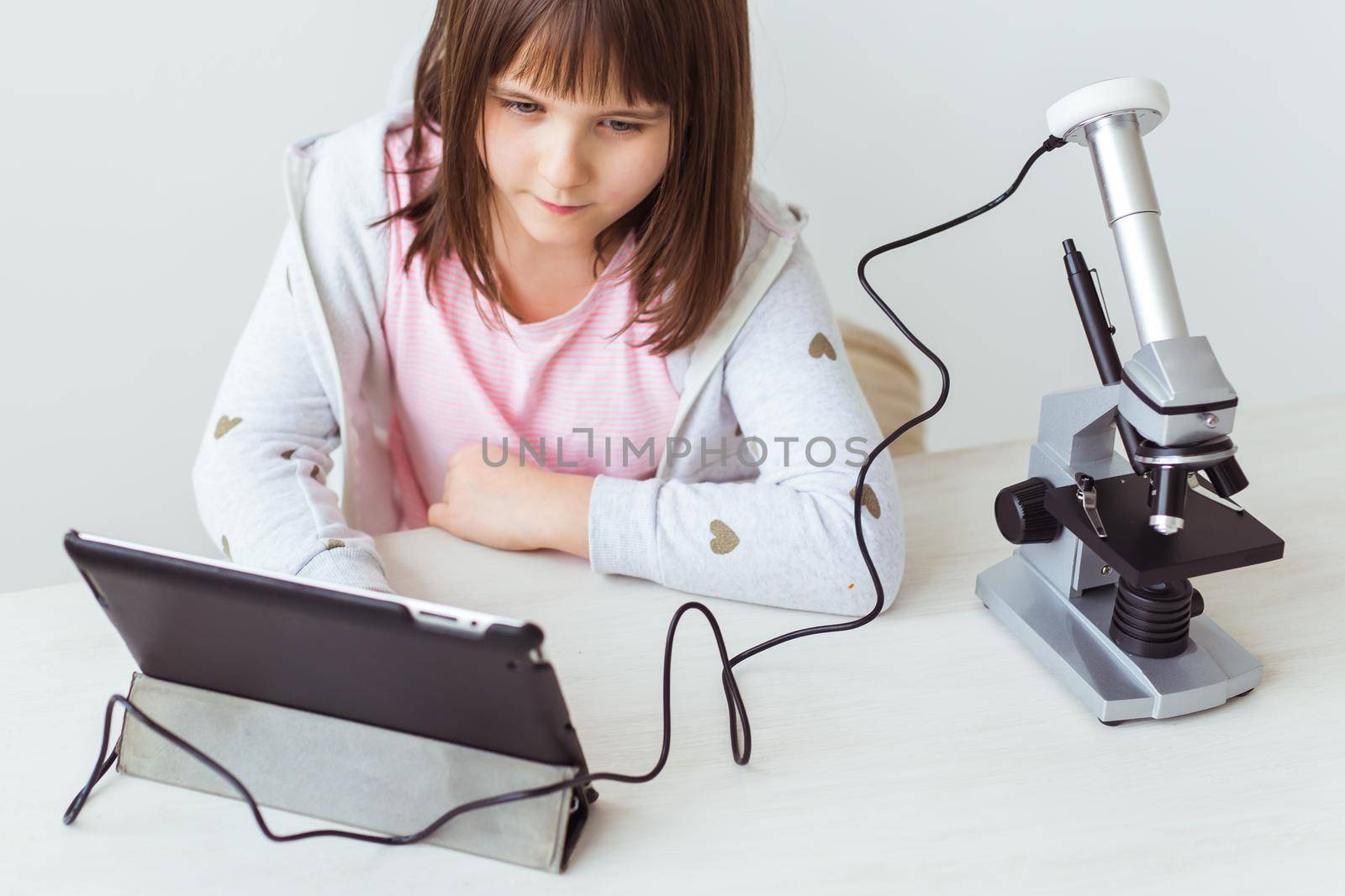 Portrait of cute little child doing homework with a digital microscope Technologies, science and children.