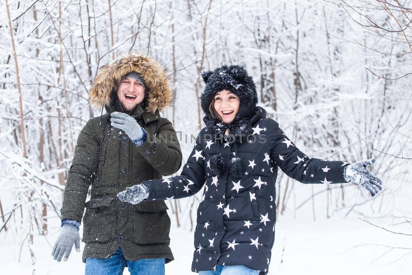 man and woman having fun and playing with snow in winter forest