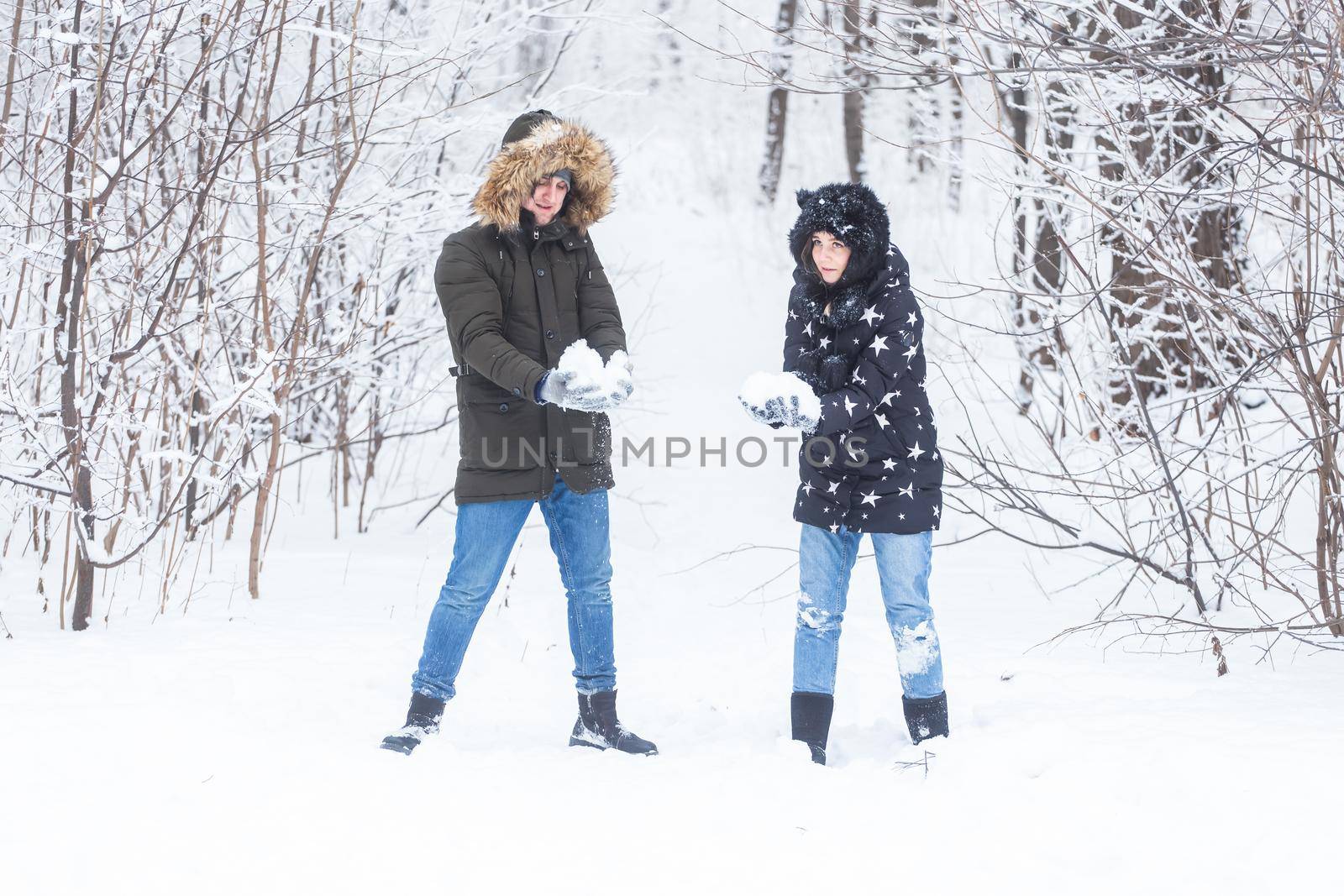 Love, relationship, season and friendship concept - man and woman having fun and playing with snow in winter forest by Satura86