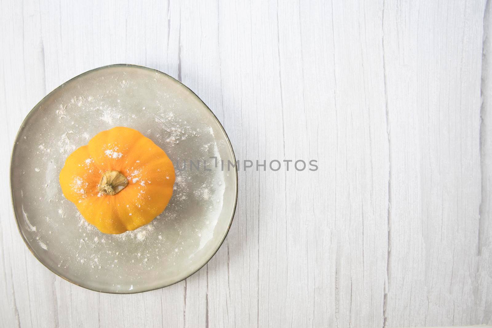 Orange pumpkin on white wooden background with copy space on natural plate top view, autumn harvest, Halloween or Thanksgiving concept space for text